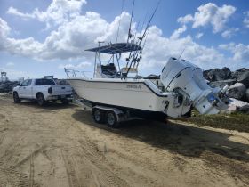 A fishing boat named 'Camila' is parked on a trailer, ready for a day on the water. The scene captures the vessel's sleek design against a backdrop of clouds and rocky terrain.