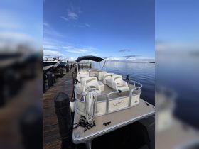 A serene view of a pontoon boat docked at the marina, showcasing its spacious seating and inviting atmosphere, perfect for leisurely outings on the water.