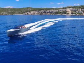 A sleek speedboat glides through the vibrant blue waters, showcasing an exhilarating day on the ocean with stunning coastal scenery in the background.