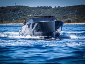 A sleek speedboat cuts through the clear blue waters, showcasing its modern design and dynamic movement — perfect for thrilling adventures on the sea.