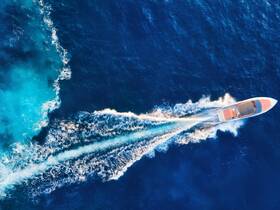 Aerial view of a speedboat cruising through deep blue waters, leaving a stunning wake behind — perfect for adventure seekers and water enthusiasts.