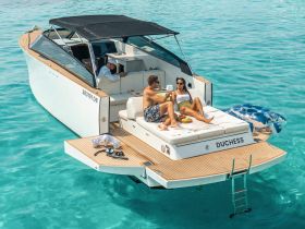 A couple enjoys a relaxing day on the deck of the yacht 'Duchess', savoring cocktails and snacks in the clear turquoise waters — an ideal setting for romantic getaways or special celebrations.