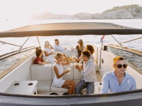 A lively group enjoys cocktails aboard a yacht during sunset, capturing the essence of celebration and camaraderie on the water.