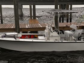 A sleek center console boat docked at a wooden pier, showcasing its design and readiness for fishing or leisure activities on the water.