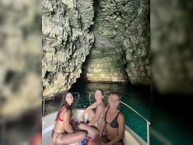 Three friends enjoy a relaxing moment on a boat inside a stunning cave, showcasing the beauty of nature and camaraderie during their adventure.