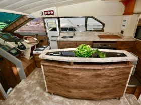 Interior view of a luxurious boat cabin featuring a well-equipped helm and kitchen area, perfect for comfortable cruising and entertaining on the water.