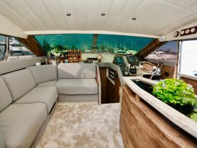 A beautifully designed interior of a boat featuring comfortable seating and a well-equipped helm, perfect for relaxing or navigating the waters.