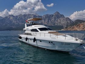 A stunning yacht named 'Legends' cruising through clear waters with a backdrop of majestic mountains, perfect for luxury getaways and scenic adventures.