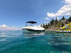 A sleek speedboat anchored in crystal-clear waters, surrounded by stunning natural scenery — perfect for summer adventures on the lake.