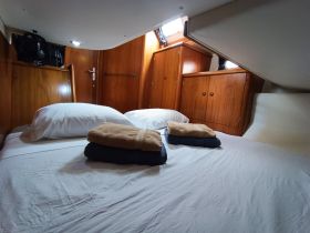 Cozy cabin interior featuring a neatly made bed with fresh linens and towels, perfect for a comfortable stay on the water.