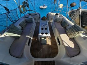 A cozy interior view of a yacht's seating area, featuring plush cushions and a stylish helm, perfect for relaxing while enjoying the beautiful turquoise waters.