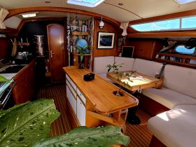 A cozy interior view of a boat's cabin featuring comfortable seating and a well-equipped kitchen area, perfect for relaxing and dining while at sea.