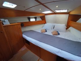 Cozy cabin interior featuring a comfortable double bed with neatly arranged towels, perfect for relaxing on a sailing adventure.