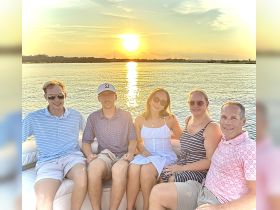 A cheerful group enjoys a sunset cruise on a pontoon boat, capturing the perfect moment of camaraderie and relaxation on the water.