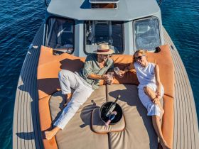 A couple enjoys a relaxing moment on the deck of a yacht, toasting with cocktails under the sun — an ideal setting for romantic getaways or special celebrations.