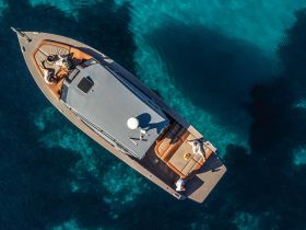 Aerial view of a group enjoying sunbathing on a luxurious yacht, surrounded by crystal-clear waters — perfect for summer getaways and relaxation on the sea.