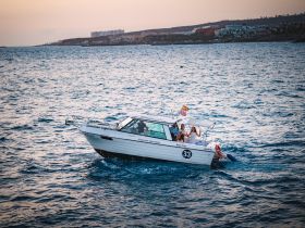 A lively group enjoys a sunset cruise aboard a boat, capturing the essence of fun and adventure on the water.