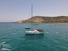 A picturesque scene featuring a sailboat anchored near a beautiful island, with guests enjoying the water — perfect for summer adventures and island exploration.