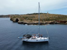 A lively group enjoys a sailing adventure on a yacht near a scenic coastline, perfect for memorable outings and celebrations on the water.