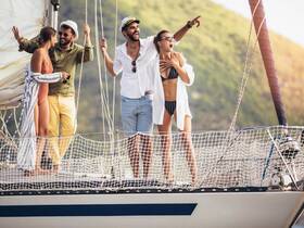 A lively group of friends enjoys a fun moment aboard a sailboat, celebrating and taking in the beautiful surroundings — perfect for memorable sailing adventures.