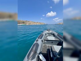 A sleek speedboat glides through clear turquoise waters, showcasing the stunning coastline and marina in the background — perfect for exploring the open sea.