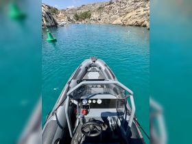 An interior view of a sleek boat helm showcasing the steering console and controls, perfect for navigating the beautiful turquoise waters.