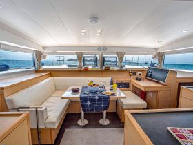 A spacious and elegantly designed interior of a yacht featuring a comfortable seating area and dining table, perfect for enjoying meals while taking in the scenic ocean views.