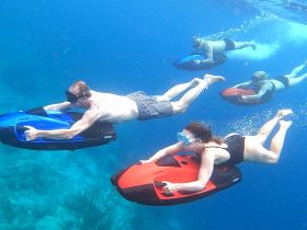 A group of adventurers enjoys an exhilarating underwater experience while using jet skis, showcasing the thrill of snorkeling and diving in crystal-clear waters.
