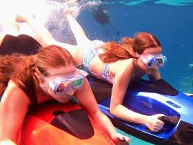 Two friends enjoy an exhilarating snorkeling experience underwater, showcasing the fun and adventure of exploring marine life.