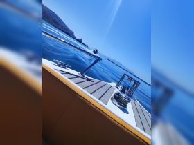 A close-up view of a sleek boat's bow cutting through calm waters, showcasing its design and the serene blue surroundings.