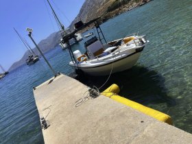 A picturesque view of a boat docked at a serene harbor, surrounded by clear waters and scenic mountains, perfect for a day of exploration.