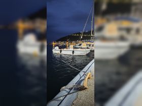 A serene night view of a boat docked at the harbor, illuminated by the lights of the nearby town, creating a picturesque scene perfect for evening strolls by the water.