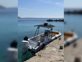 A sleek speedboat docked at a serene waterfront, showcasing its modern design against a backdrop of calm waters and distant islands.