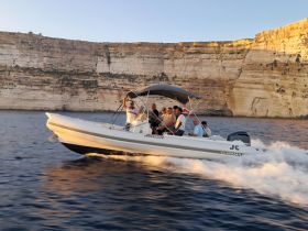 A lively group enjoys a thrilling ride on a boat against a stunning cliff backdrop, capturing the essence of adventure on the water.