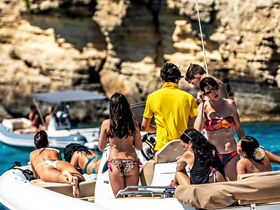 A lively group enjoys a summer day on a boat, showcasing fun and camaraderie against a stunning coastal backdrop.