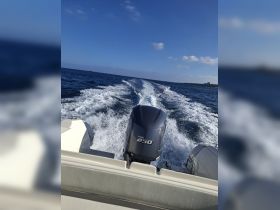A dynamic view of a speedboat in motion, showcasing the powerful Yamaha 250 engine and the wake it creates on the open water.