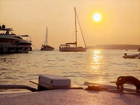 A picturesque sunset view featuring various yachts on the water, creating a serene atmosphere perfect for evening cruises and relaxation.