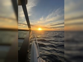 A stunning sunset view from the side of a boat, capturing the serene beauty of the ocean as the sun dips below the horizon.