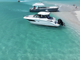 A stunning aerial view of a sleek speedboat anchored in crystal-clear turquoise waters, showcasing the beauty of a perfect day on the water.