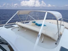 A serene view of a comfortable lounge area on a boat, featuring plush seating and towels, perfect for relaxing under the sun while enjoying the open sea.