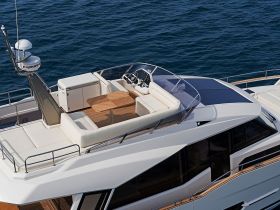 An elegant interior view of a yacht's upper deck, showcasing comfortable seating and a helm area, perfect for relaxing while cruising on the water.