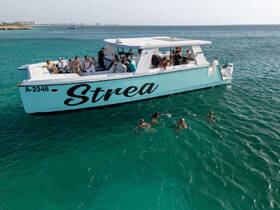 A lively group enjoys snorkeling in clear turquoise waters, with the vibrant boat 'Strea' providing a perfect backdrop for a fun day on the water.