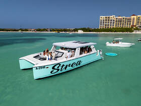 A lively group enjoys a day on the water aboard the 'Strea' boat, surrounded by stunning turquoise waters — perfect for celebrations and group outings.