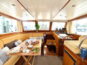 The interior of a beautifully designed boat featuring a cozy seating area and helm, perfect for relaxing or navigating the waters.