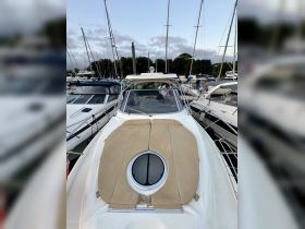 A top-down view of a yacht docked at the marina, showcasing its sleek design and comfortable sunbathing area.