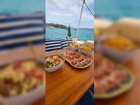 A beautifully arranged spread of charcuterie and salads on a boat's dining table, perfect for enjoying meals while cruising on the water.