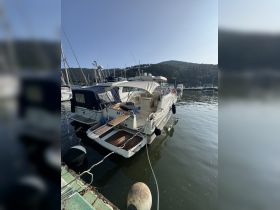 A sleek yacht docked at a marina, surrounded by other vessels and scenic hills in the background — perfect for a day on the water.