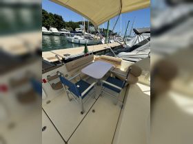 A cozy seating area inside a boat, featuring a table and chairs, perfect for dining or relaxing while enjoying the marina views.