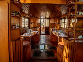 Interior view of a beautifully designed boat cabin featuring elegant dining arrangements and cozy seating, perfect for intimate gatherings or dining experiences on the water.