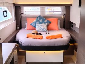 Cozy interior cabin of a boat featuring a comfortable bed adorned with vibrant pillows and towels, perfect for relaxation during a sailing adventure.